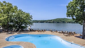 A swimming pool with lounge chairs and a view of a lake. - Baypoint Village 545 - 3 bdrm condo in Osage Beach (Osage Beach)