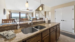 A kitchen with granite countertops, a double sink, wooden cabinets, and a view of the outdoors. - Baypoint Village 545 - 3 bdrm condo in Osage Beach (Osage Beach)