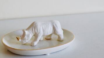 Una escultura de cerámica blanca de un oso sobre un plato blanco con borde dorado.