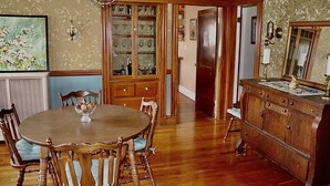 Une salle à manger avec une table et des chaises en bois, un buffet et un papier peint à motifs floraux.