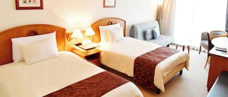 A hotel room with two beds, a desk, and a chair.