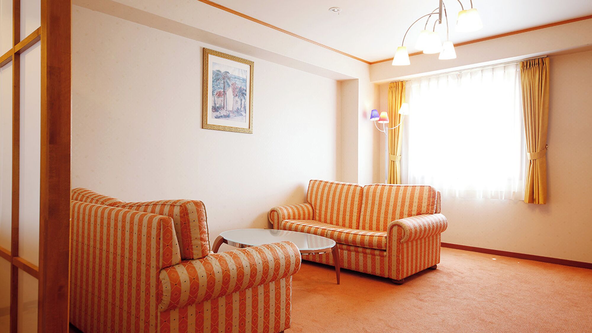 A living room with two striped armchairs, a small round table, and a single window with curtains.