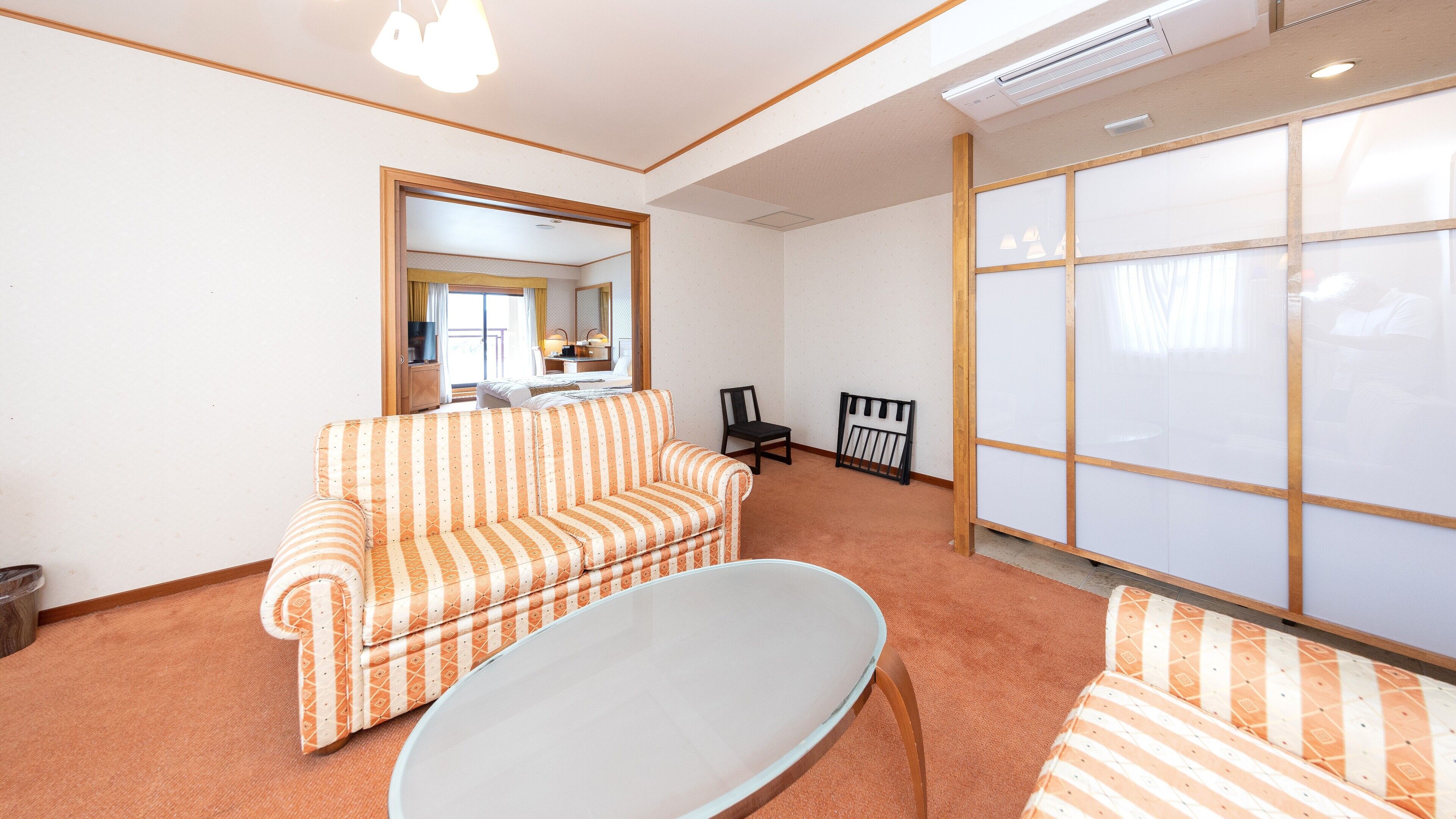A room with a striped sofa, a white table, a mirror, and a sliding door.