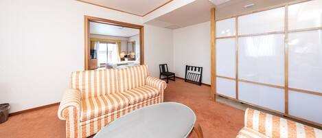 A room with a striped sofa, a white table, a mirror, and a sliding door.