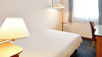 A hotel room with a bed, a desk, a lamp, and a chair.