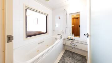 A modern bathroom with a bathtub, a shower, and a vanity with a mirror.