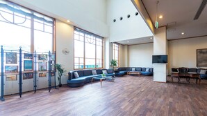 A spacious room with a large sectional sofa, a coffee table, and a TV mounted on the wall.