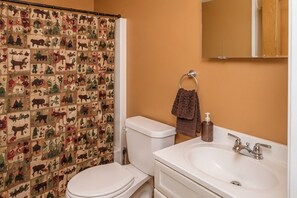 A bathroom with a toilet, sink, and shower curtain featuring animal prints.