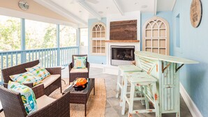 A covered outdoor seating area with wicker furniture, a fireplace, and a view of the outdoors. - Private Home-Walk to Beach & Town-Dog Friendly-Screened Porch-Fenced Yard (Folly Beach)