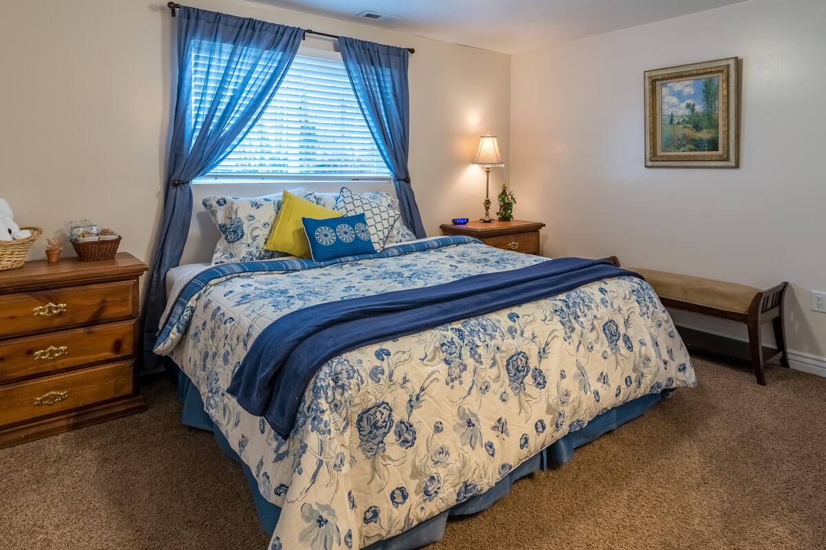 Une chambre à coucher avec un lit, une table de chevet, une lampe, une commode et un tableau au mur.