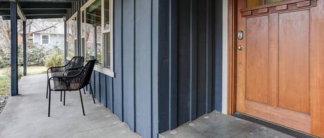 Eine überdachte Veranda mit zwei Stühlen und einer Holztür.