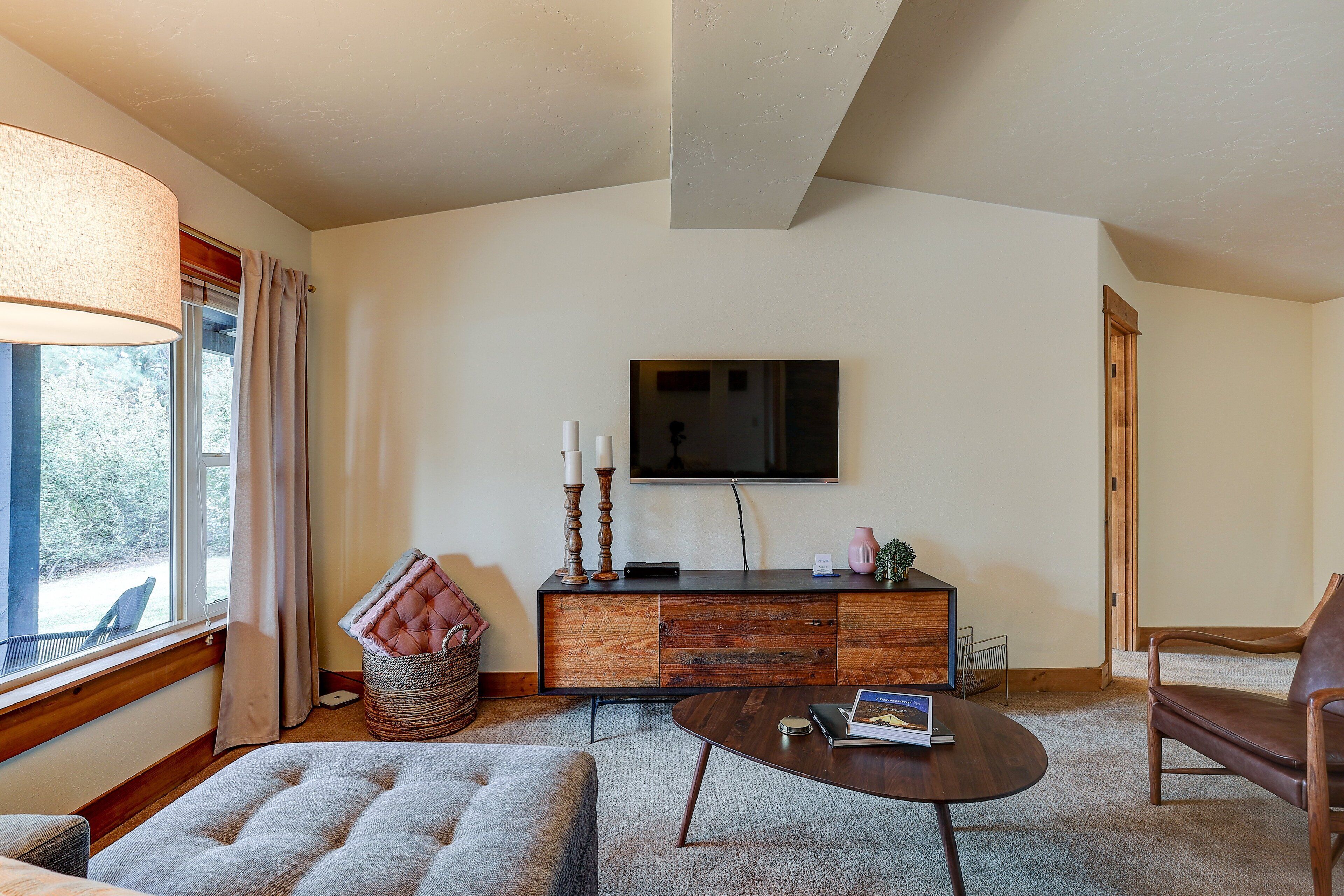 A cozy living room with a sofa, a coffee table, a wooden cabinet, and a television on the wall.