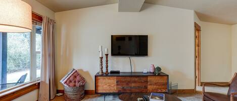 A cozy living room with a sofa, a coffee table, a wooden cabinet, and a television on the wall.