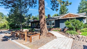 Una casa moderna con un gran árbol en el frente, un camino de entrada pavimentado y un buzón con el número 510.