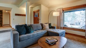 Una sala de estar con un sofá seccional, una mesa de centro y un ventanal con vistas al exterior.