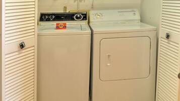 A compact laundry room with a front-loading washer and dryer, a control panel, and a door with a handle.