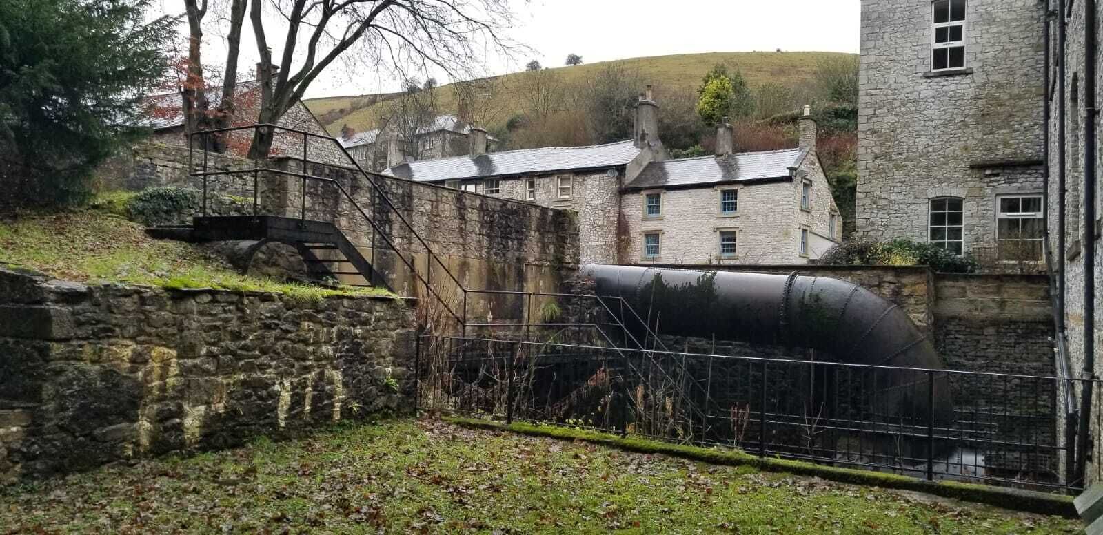 A stone building with a staircase leading to a metal gate.