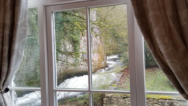 Una ventana con vista a un paisaje rocoso y un arroyo.