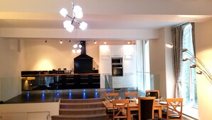 Una cocina moderna con electrodomésticos integrados, un comedor con mesa y sillas, y un ventanal que proporciona luz natural.