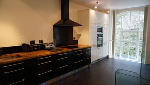 Una cocina moderna con encimera de madera, armarios negros y un ventanal que proporciona luz natural.