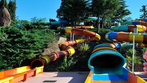 Ein Wasserpark mit mehreren bunten Wasserrutschen und einer felsigen Landschaft im Hintergrund.