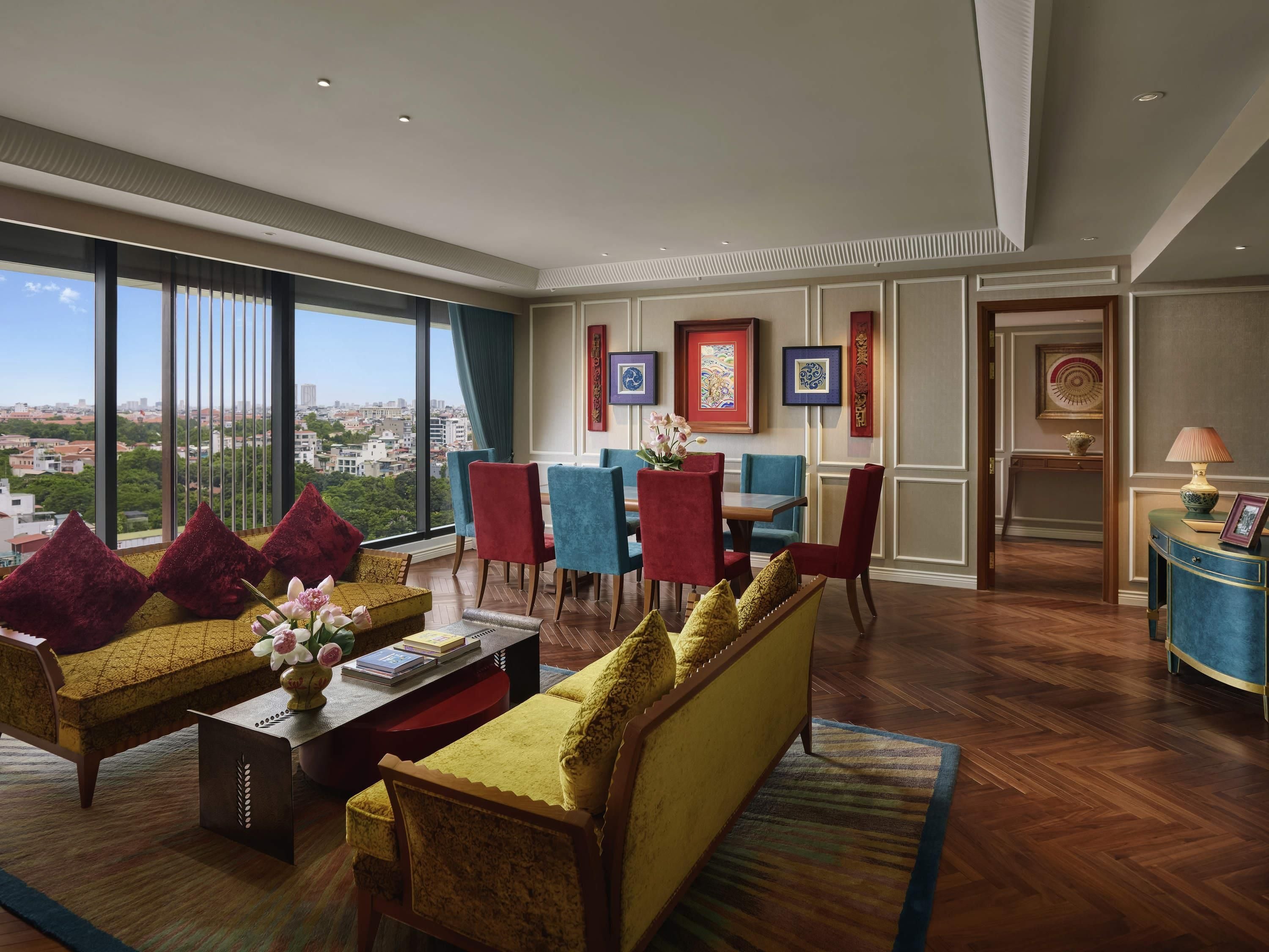 A spacious living area with a large window, a dining set, and a view of the city.