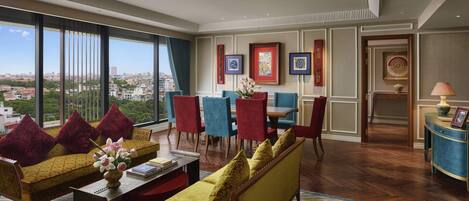 A spacious living area with a large window, a dining set, and a view of the city.