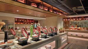 A buffet area with multiple food stations, including bowls of soup and salads, and a variety of condiments and utensils. - Grand Mercure Hanoi (Hanoi)