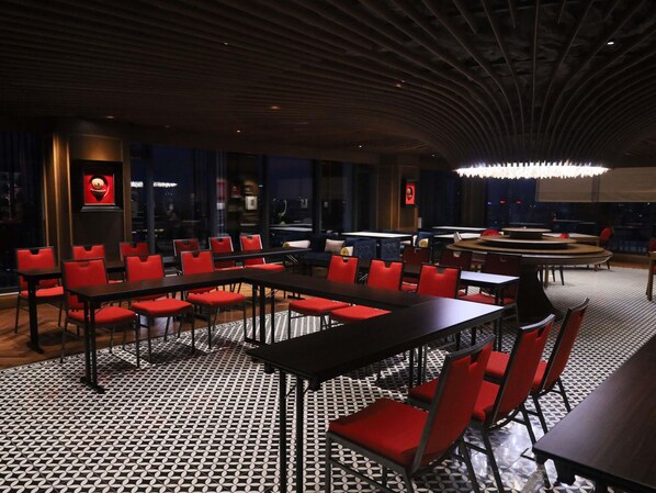 Un restaurant avec des chaises et des tables rouges, un sol Ă motifs et un plafond au design moderne.
