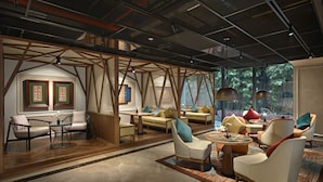 A modern hotel lobby with a wooden ceiling structure, comfortable seating areas, and large windows offering a view of greenery. - Grand Mercure Hanoi (Hanoi)