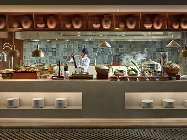 A kitchen with a chef preparing food, a variety of cooking utensils, and a display of copper pots.