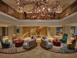A spacious lobby with a grand staircase, modern seating, and a decorative chandelier. - Grand Mercure Hanoi (Hanoi)