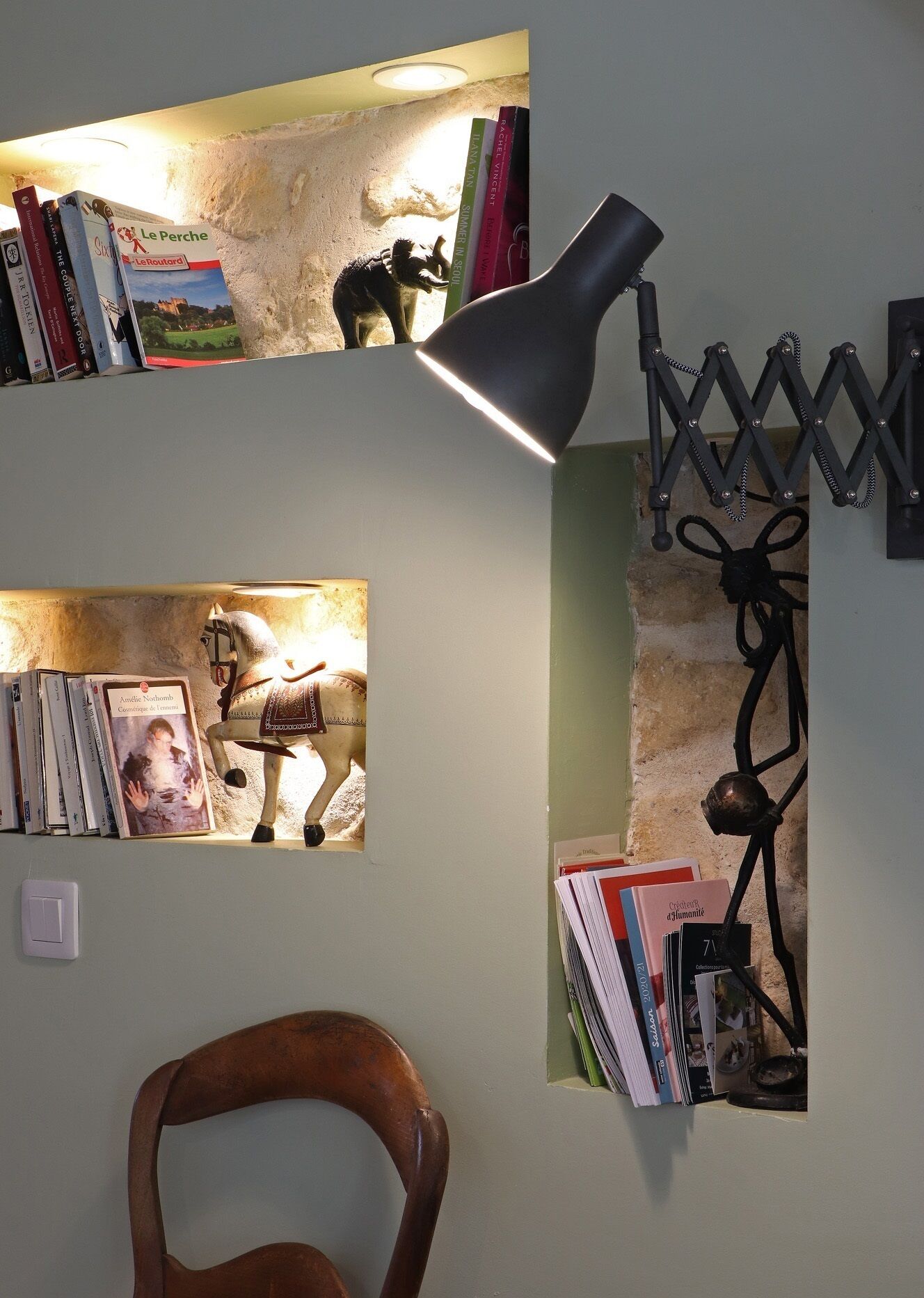 Una habitación con una estantería, una lámpara de escritorio y una silla.