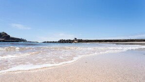 A sandy beach with gentle waves, a rocky breakwater, and a clear blue sky. - Home2Book Ocean View Bajamar Natural Pool & Beach (Bajamar)