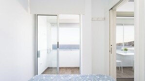 A bedroom with a patterned bedspread, a sliding glass door leading to a balcony with a view of the sea. - Home2Book Ocean View Bajamar Natural Pool & Beach (Bajamar)