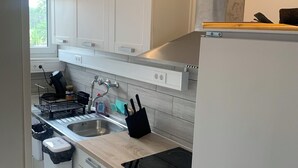 Una cocina moderna con armarios blancos, un lavamanos de acero inoxidable, un horno empotrado y una estufa negra.