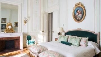 Une chambre à coucher classique avec un grand lit, une commode, un miroir et une cheminée.
