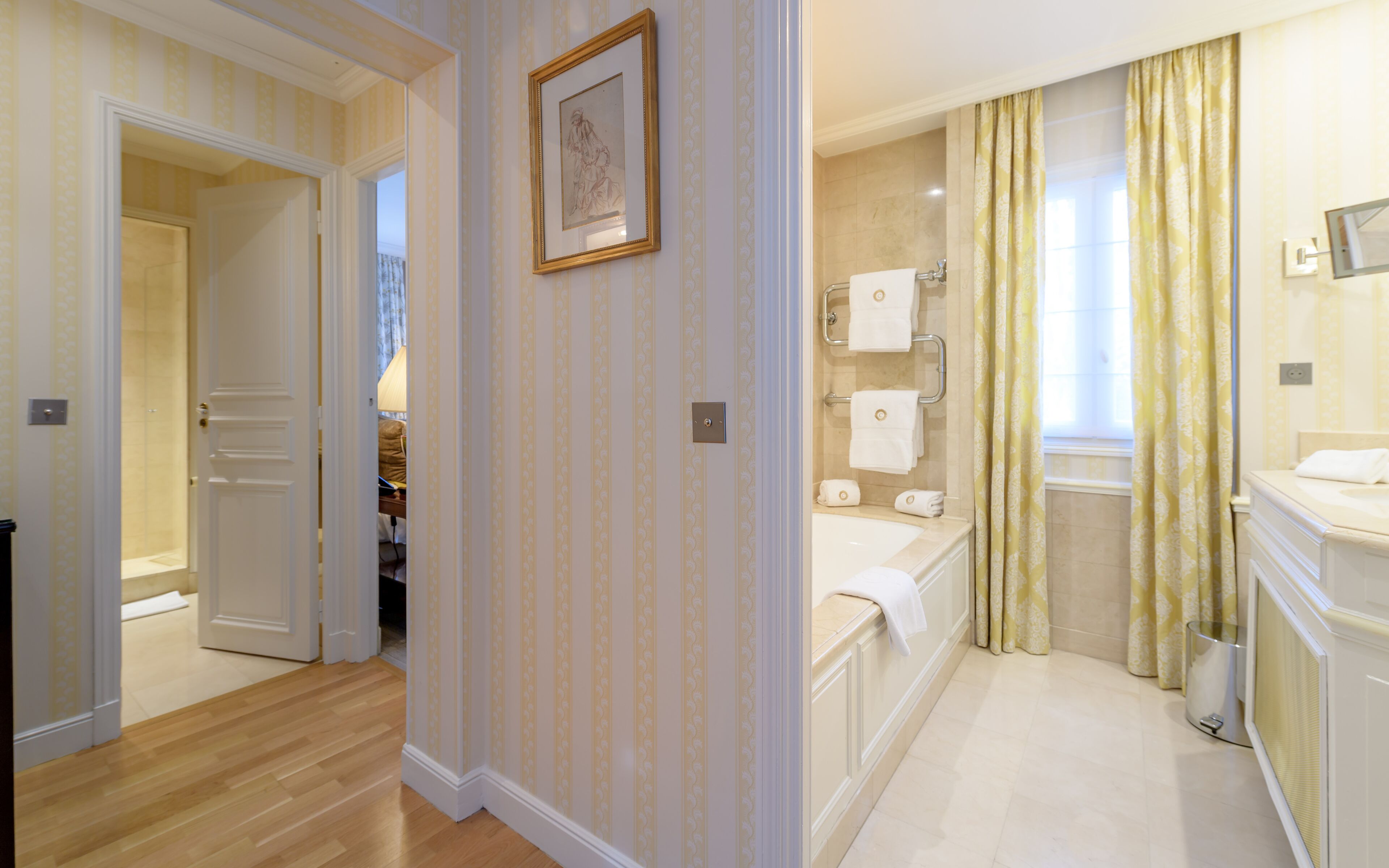 Une chambre d’hôtel avec une salle de bain, un couloir et une porte donnant sur une autre pièce.