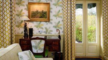 Une pièce comprenant un bureau, une chaise, une lampe et un tableau encadré accroché au mur.