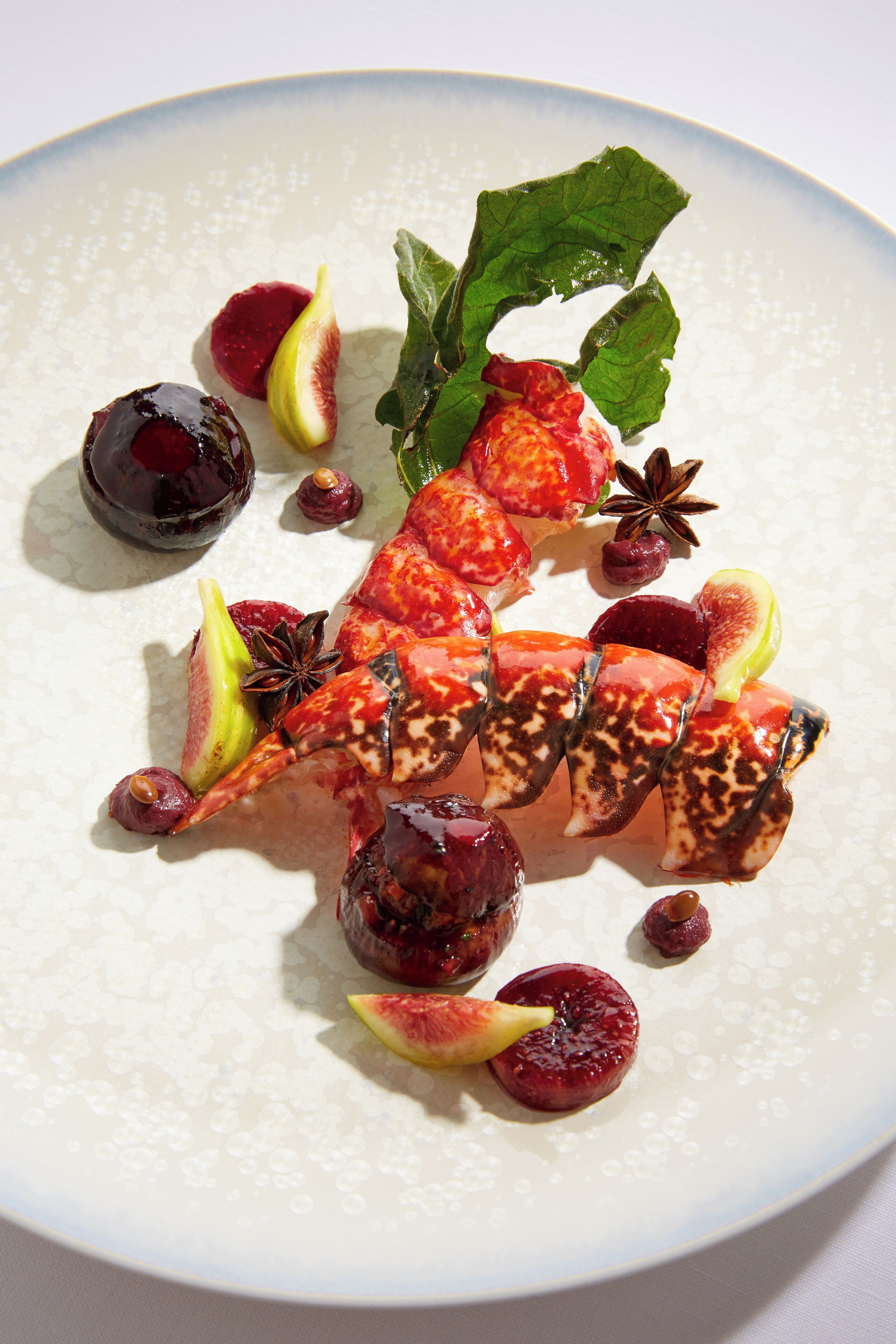 A plate with various fruits and a mint leaf.