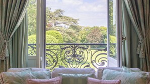 Una habitación con un ventanal grande, cortinas verdes y un banco acolchado con almohadas.