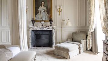 A classic room with a fireplace, a portrait, and a comfortable seating area.