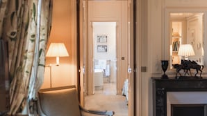 Habitación de hotel con zona de estar, chimenea y pasillo que conduce a un baño.
