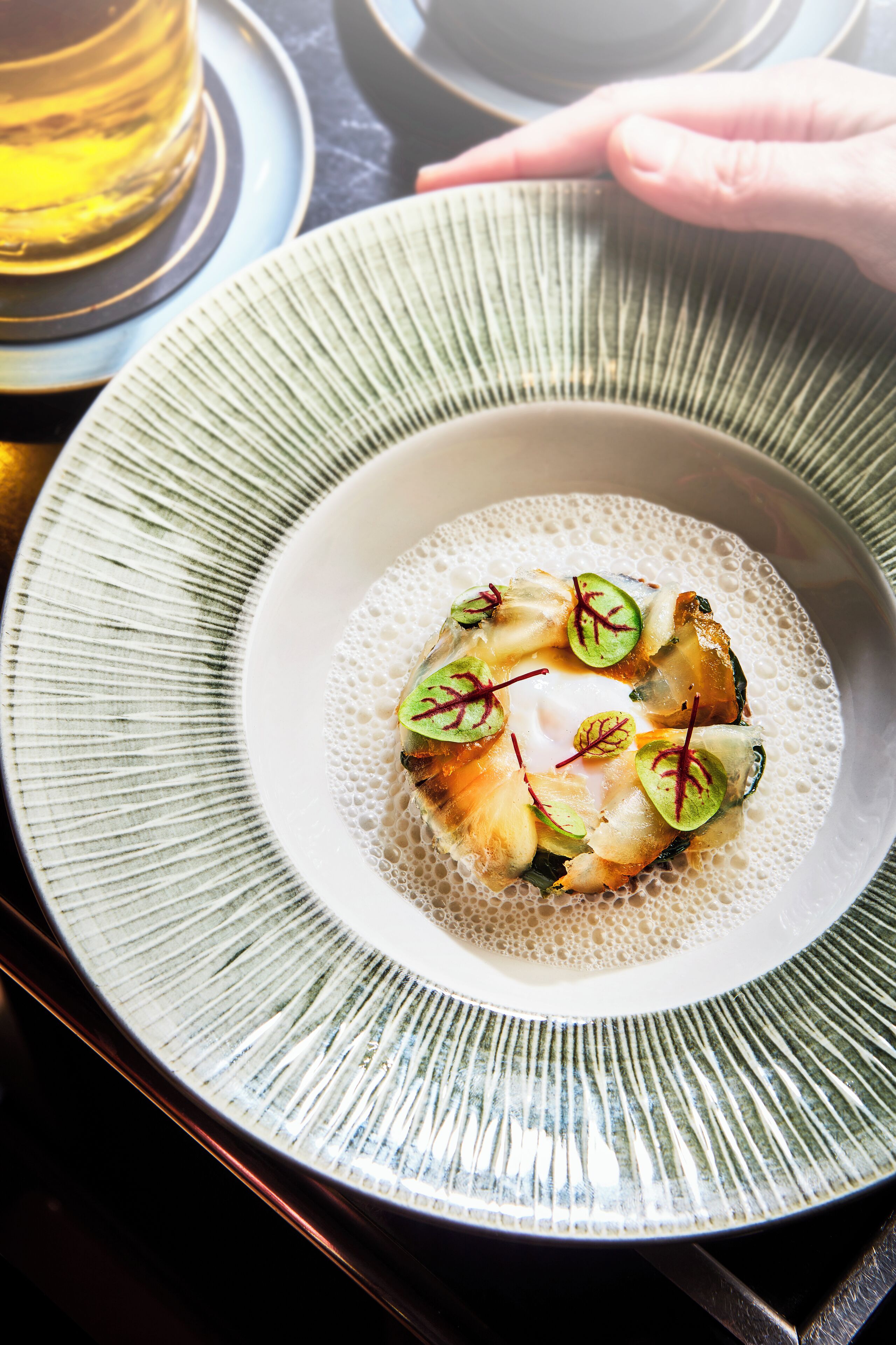 A plate of food with a hand reaching for it.