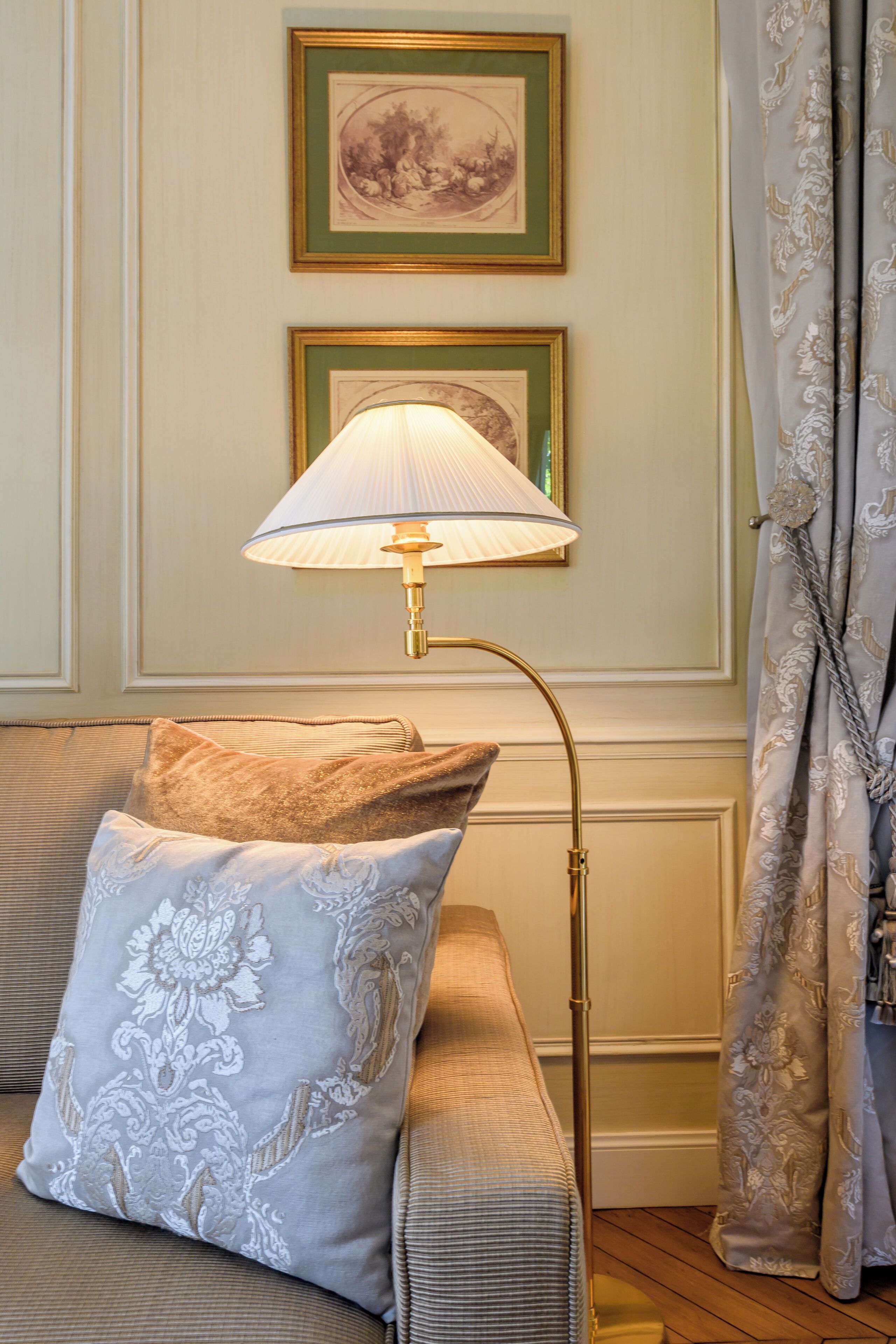 A room with a sofa, a lamp, and two framed pictures on the wall.