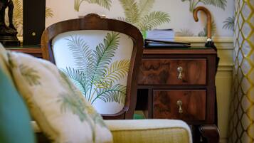 A room with a wooden chair featuring a leaf pattern, a wooden cabinet with drawers, and a patterned wall.