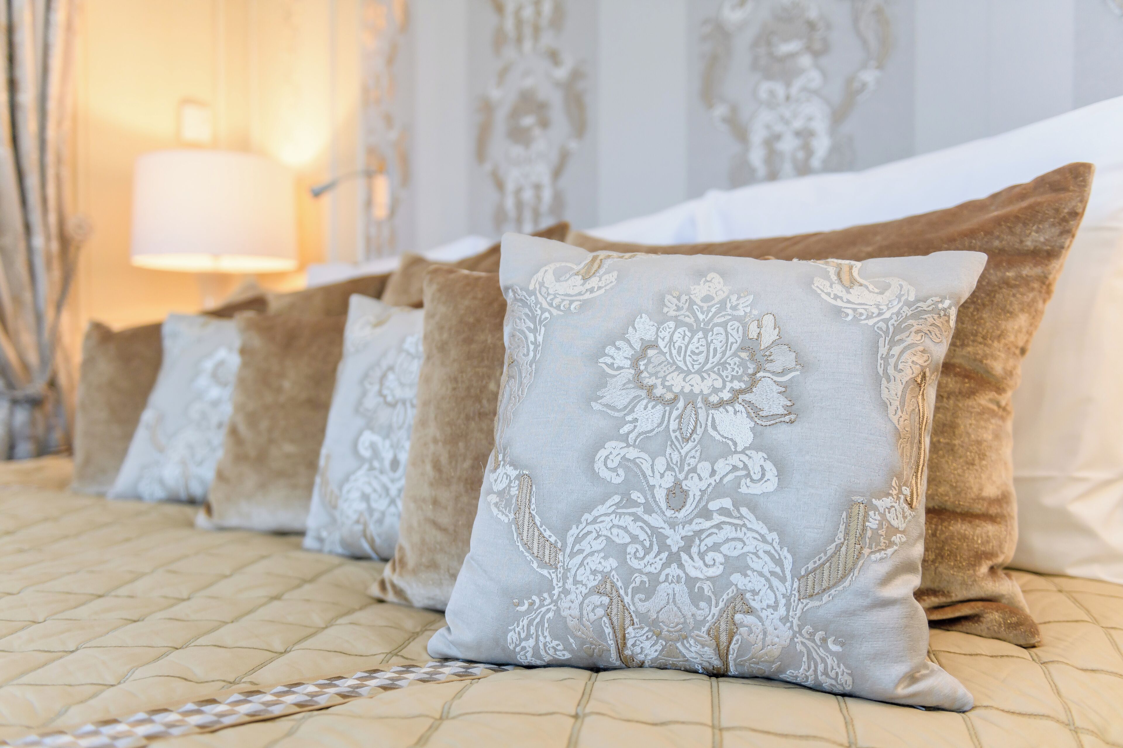 A bed with a quilted headboard and multiple pillows with intricate patterns.