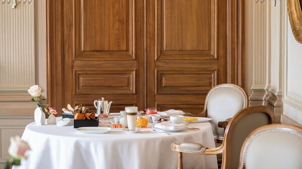 Une table à manger dressée pour le petit-déjeuner, avec une variété d’aliments, une théière et un vase rempli de fleurs.