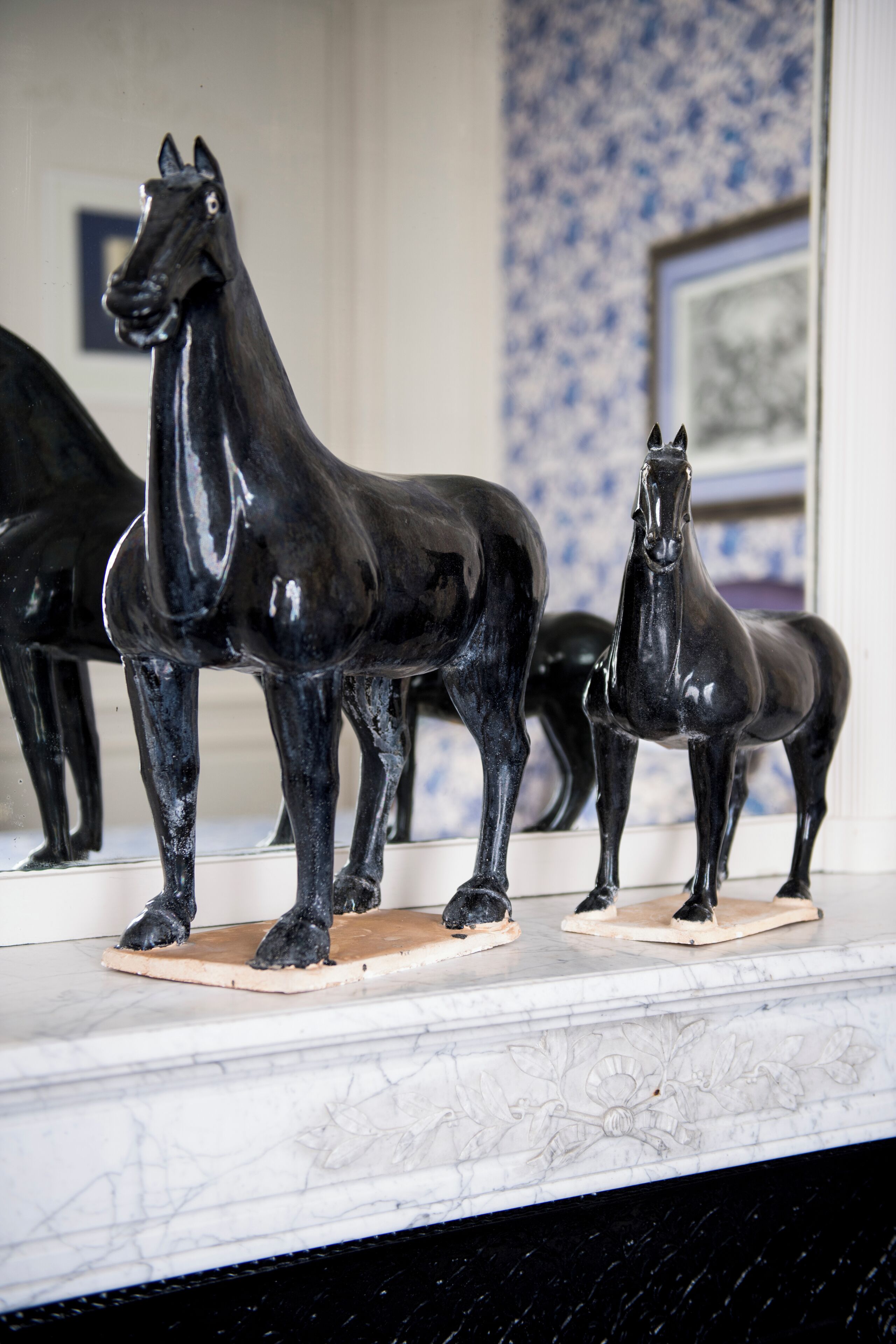 Two black horse sculptures on a marble surface.