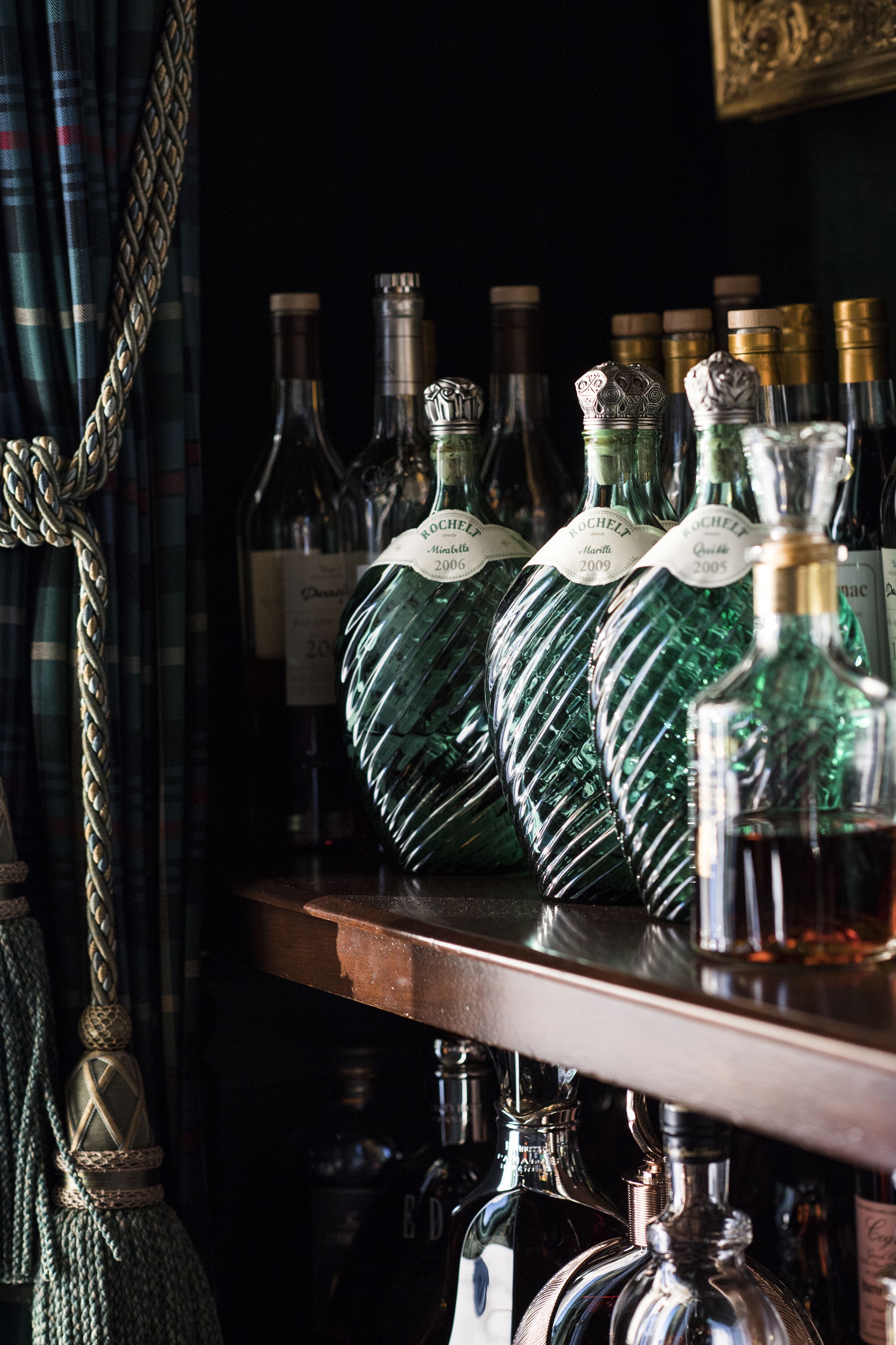 A bar area with several bottles of liquor, including a prominent green bottle labeled "ROCHELF" and a smaller bottle labeled "ED."